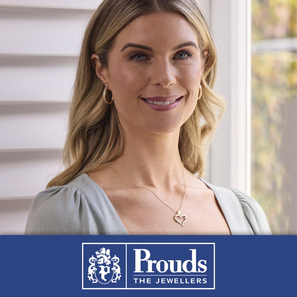 A woman wearing beautiful earrings and necklace. Prouds logo at the bottom, 'Prouds the jewellers'.